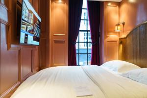 a bedroom with a bed with a tv and a window at Mimi's Hotel Soho in London