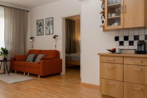 a living room with a orange couch and a kitchen at Fresh Apartment with Terrace + Free Parking in Graz