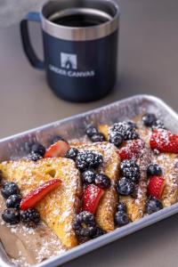 a plate of french toast with berries and a cup of coffee at Under Canvas Acadia in Surry