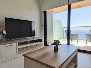 a living room with a flat screen tv and a table at SUNSET WAVES blue sky apartment in Benidorm