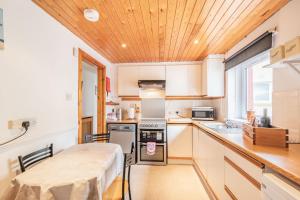 a kitchen with white cabinets and a wooden ceiling at Creel Cottage in Eyemouth