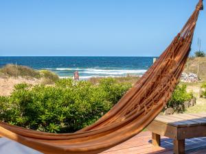 a hammock on a deck with the beach at Cabañas Kundalini Punta del Diablo in Punta Del Diablo