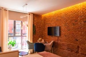 a living room with a brick wall with a tv at Ferrari Suites in Valladolid