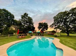 een zwembad in een tuin met tafels en parasols bij Galvanized America Inn & Art Gallery in Doylestown