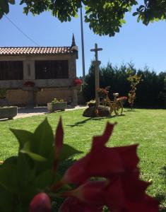 a church with a cross in a yard with a red flower at HOTEL O NOSO BAR in Cambados