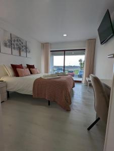 een slaapkamer met een groot bed en een glazen schuifdeur bij Silvaapartments in Praia da Barra