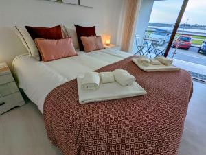 a bedroom with a large bed with two towels on it at Silvaapartments in Praia da Barra