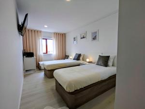 um quarto de hotel com duas camas e uma janela em Silvaapartments em Praia da Barra