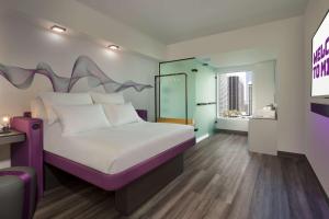 um quarto com uma cama grande e uma cabeceira de cama roxa em YOTEL Miami em Miami