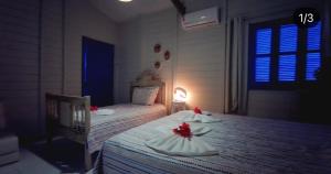 1 dormitorio con 2 camas con flores rojas. en Casa na praia do saco - Casa Jardim praia do saco, en Praia do Saco