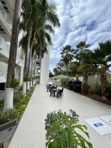 una pasarela con palmeras, mesas y bancos en Edificio Bay Point Apartmento 307, en San Andrés