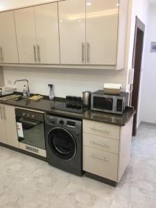 a kitchen with a washing machine and a microwave at New and cosy apartment in Amman (Al Weibdeh) in Amman