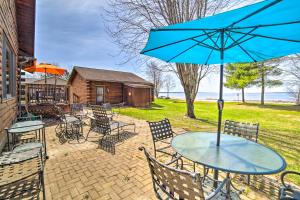 a table with a blue umbrella on a patio at Beachfront Lake Michigan Log Cabin with Sauna! in Rapid River