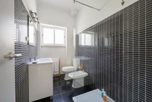 a bathroom with a white toilet and black tiles at Sunset Balcony Apartment, By TimeCooler in Lisbon