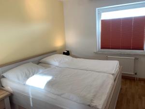 - une chambre avec un lit doté de draps blancs et une fenêtre dans l'établissement Kleine Brise Apartment 5, à Büsum