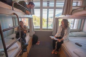 Absoloot Hostel Queenstown في كوينزتاون: يجلس شخصان في غرفة مع سرير بطابقين