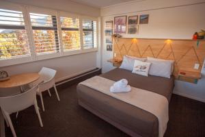 1 dormitorio con cama, mesa y escritorio en Absoloot Hostel Queenstown en Queenstown