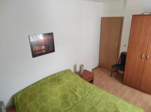 - une chambre avec un lit vert et une armoire en bois dans l'établissement Apartment Karlo, à Supetar