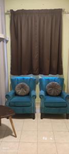 twee blauwe stoelen in een woonkamer met een raam bij Cikgu Azue Homestay in Ampang