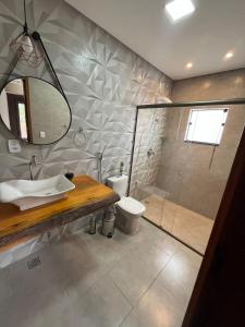 uma casa de banho com um chuveiro, um lavatório e um WC. em Pouso Primavera em Tiradentes