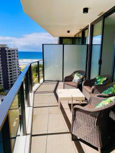 a balcony with chairs and a table and the ocean at Koko luxury apartment in Broadbeach in Gold Coast