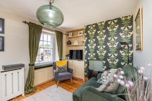 a living room with a green couch and a chair at 4 Canalside Cottages in Towcester