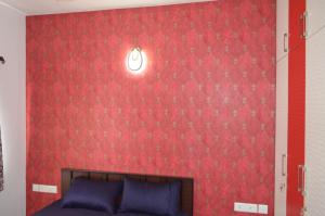 - une chambre dotée d'un mur rouge avec une lumière au-dessus d'un lit dans l'établissement Oviyam Sea view Apartment, feel like home, à Chennai