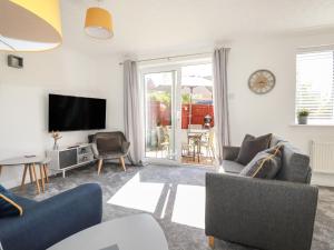 a living room with a tv and a couch and chairs at Sea Rest in Bude