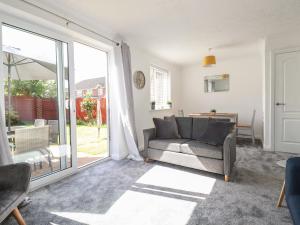 a living room with a couch and a sliding glass door at Sea Rest in Bude