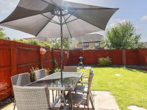 a patio table with an umbrella in a backyard at Sea Rest in Bude