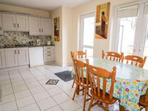 uma cozinha com mesa e cadeiras e uma cozinha com armários brancos em Bridgetown Cottage em Kerrykeel