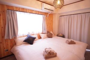 a bedroom with a white bed with towels on it at 北新宿ウッドウォールステイ in Tokyo