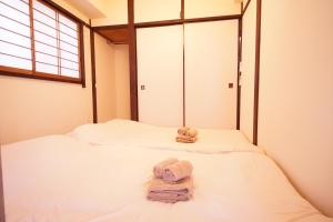 two towels on a bed in a room at 北新宿ウッドウォールステイ in Tokyo