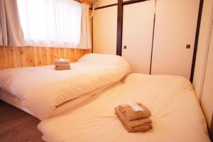 two beds in a room with towels on them at 北新宿ウッドウォールステイ in Tokyo