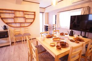a dining room with a wooden table and a television at 北新宿ウッドウォールステイ in Tokyo