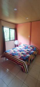 Un dormitorio con una cama con una manta de colores. en Starfish Cahuita's House - Casa Vacacional en Cahuita