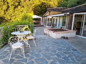 eine Terrasse mit einem Tisch und Stühlen sowie einem Whirlpool in der Unterkunft Casa Di Vadella in Santʼ Andrea-di-Cotone