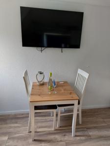 a wooden table with three chairs and a television on a wall at Backbord in Wangerland