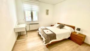 1 dormitorio con cama, escritorio y lavamanos en Apartamento Sweet Home Vitoria, en Vitoria-Gasteiz
