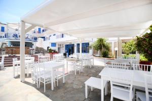 un restaurante con mesas blancas y sillas blancas en Kirki Village-Adults Only en Panormos Rethymno