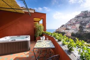 einen Balkon mit einem Whirlpool und einem Tisch in der Unterkunft Hotel Savoia in Positano