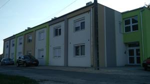 a large building with cars parked in a parking lot at River Side Apartman in Kalocsa