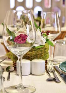 un tavolo con due bicchieri da vino e un cesto di fiori di Hotel Mirella a Castiglione della Pescaia