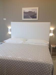 a bedroom with a white bed with a picture on the wall at Hotel Mirella in Castiglione della Pescaia