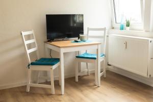 a small desk with two chairs and a television at Apartments Oberkochen in Oberkochen