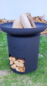 Une poubelle noire avec un tas de bois. dans l'établissement Stará Celnice Kvilda, à Kvilda