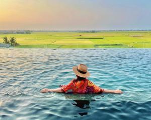 a woman in the water with a hat in the water at Lasenta Boutique Hotel Hoian in Hoi An