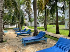una fila de tumbonas azules bajo palmeras en Royal Palms Apartment A4, en Mombasa