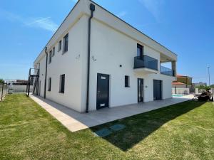 a white building with black doors on a grass field at Vila Softic Amra in Umag