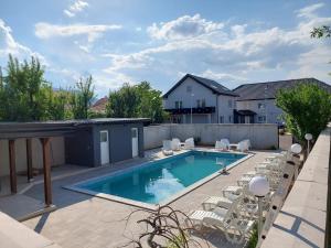 a swimming pool with lounge chairs and a house at MB apartmani Sarajevo in Sarajevo